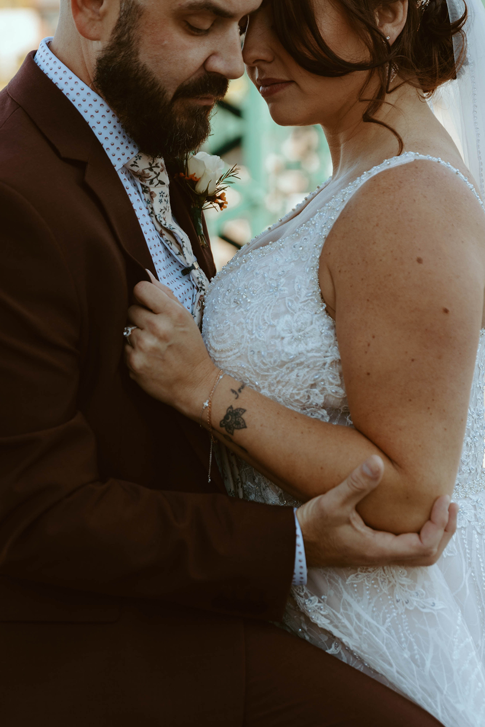 Groom gently caresses bride's arm during bridal portraits in downtown Grand Rapids.